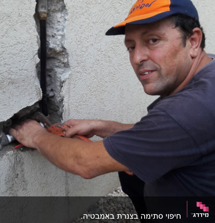 אדם מתקן צינור מים בקיר עם מפתח צינורות